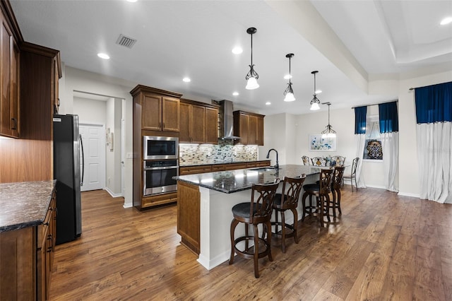 33219 Kateland Dr, Wesley Chapel, FL 33545 - kitchen featuring appliances with stainless steel finishes, a sink, wall chimney range hood, dark wood finished floors, and recessed lighting