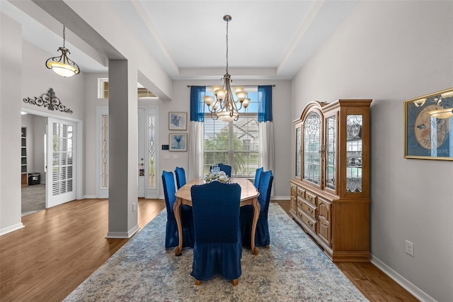 33219 Kateland Dr, Wesley Chapel, FL 33545 - dining space with a chandelier, wood finished floors, a raised ceiling, baseboards, and a high ceiling