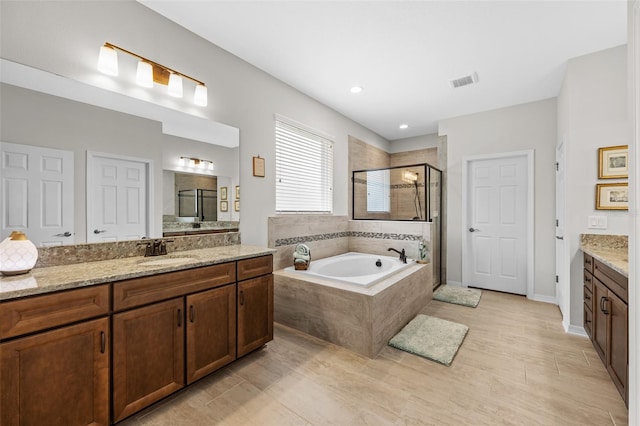 33219 Kateland Dr, Wesley Chapel, FL 33545 - bathroom featuring a shower stall, vanity, a bath, wood finished floors, and recessed lighting