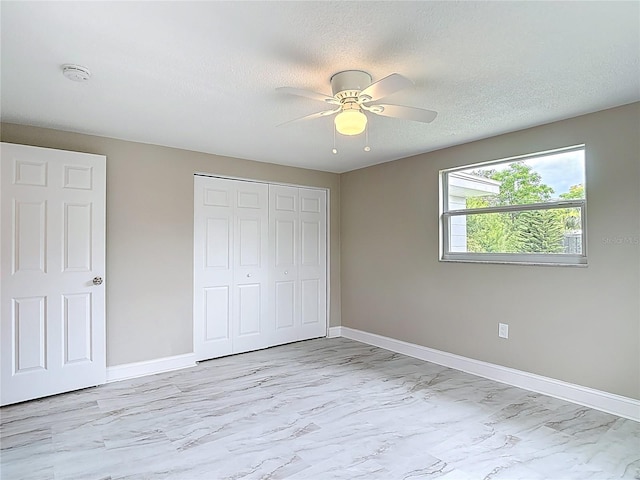 8329 Gulf Way, Hudson, FL 34667 - unfurnished bedroom featuring a closet, light marble finish flooring, baseboards, a ceiling fan, and a textured ceiling