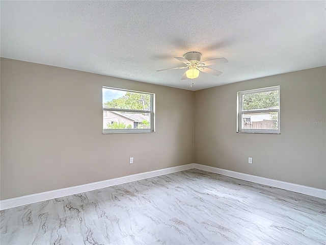 8329 Gulf Way, Hudson, FL 34667 - unfurnished room featuring marble look tile flooring, baseboards, a ceiling fan, and a textured ceiling