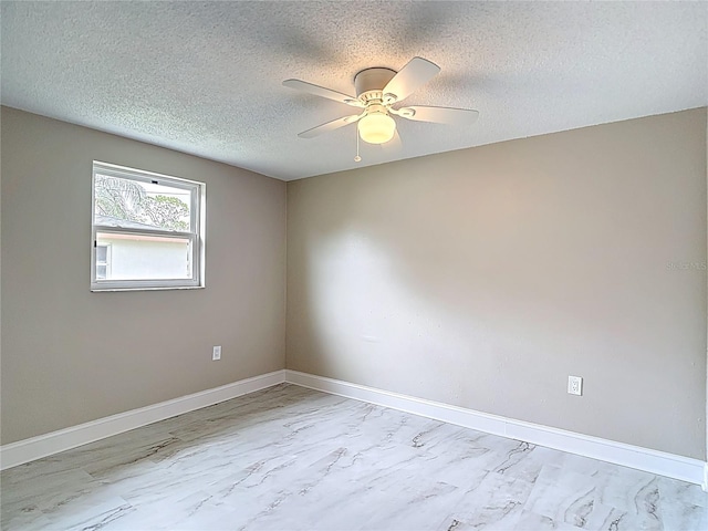 8329 Gulf Way, Hudson, FL 34667 - empty room with baseboards, ceiling fan, marble look tile flooring, and a textured ceiling