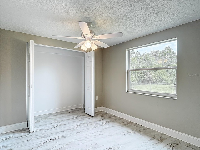 8329 Gulf Way, Hudson, FL 34667 - unfurnished bedroom with light marble finish flooring, a closet, a textured ceiling, baseboards, and a ceiling fan