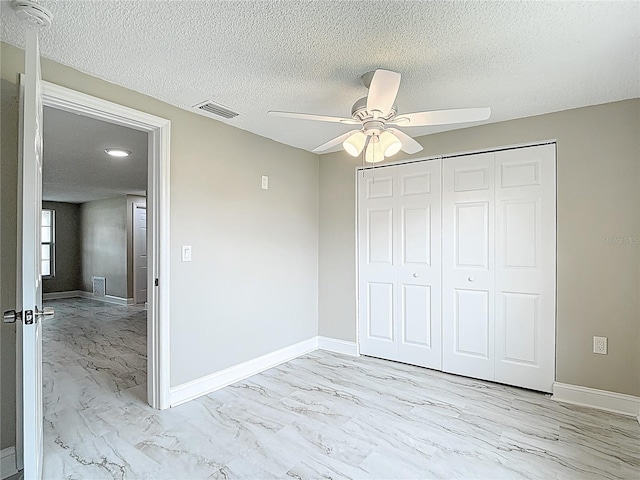 8329 Gulf Way, Hudson, FL 34667 - unfurnished bedroom featuring light marble finish flooring, baseboards, a closet, a textured ceiling, and a ceiling fan