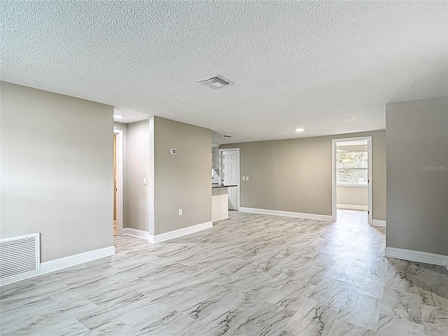 8329 Gulf Way, Hudson, FL 34667 - empty room featuring light marble finish floors, a textured ceiling, and baseboards
