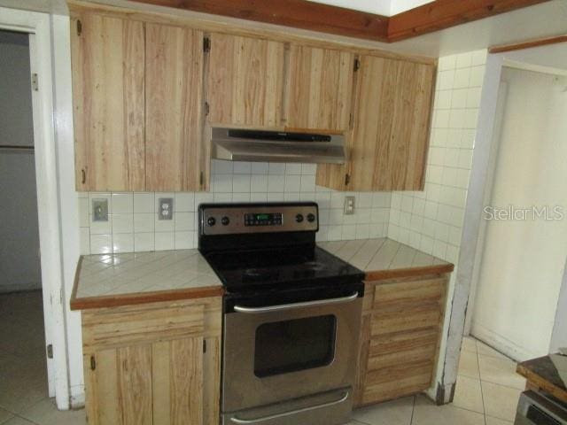 5190 Starling Dr, Mulberry, FL 33860 - kitchen featuring under cabinet range hood, stainless steel range with electric stovetop, tile counters, and light tile patterned flooring