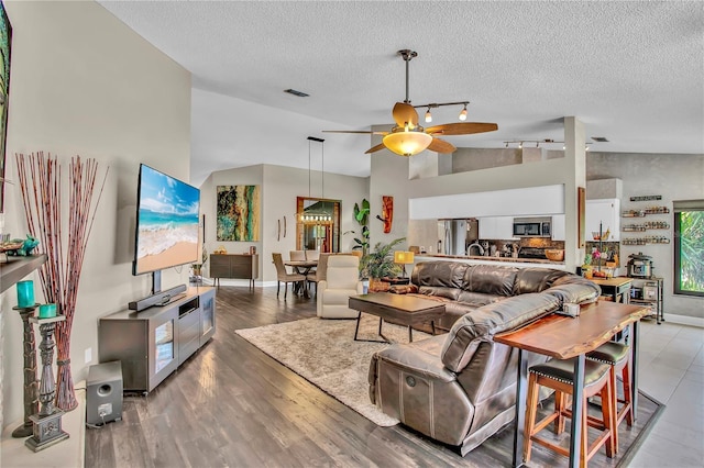 12219 Steppingstone Blvd, Tampa, FL 33635 - living room featuring a ceiling fan, vaulted ceiling, a textured ceiling, rail lighting, and wood finished floors