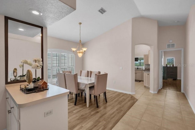 241 Royal Palm Way, Spring Hill, FL 34608 - dining area with a chandelier, baseboards, arched walkways, light wood-style floors, and vaulted ceiling