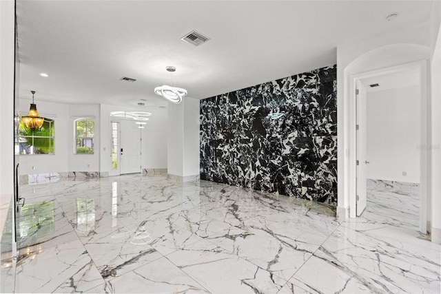 2238 Shirecrest Cove Way, Lutz, FL 33558 - unfurnished room featuring marble tiled flooring, a chandelier, arched walkways, and an accent wall