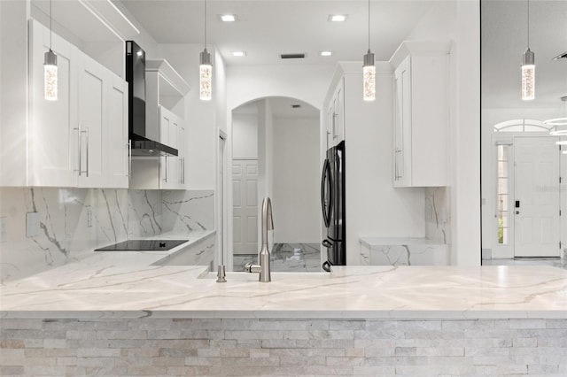 2238 Shirecrest Cove Way, Lutz, FL 33558 - kitchen featuring black appliances, wall chimney exhaust hood, arched walkways, white cabinetry, and light stone counters