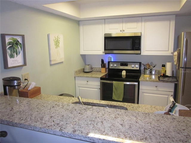 2616 Cove Cay Dr Unit 104, Clearwater, FL 33760 - kitchen with stainless steel appliances, white cabinets, a sink, and light stone counters