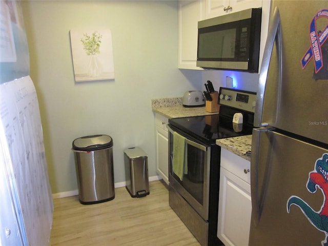 2616 Cove Cay Dr Unit 104, Clearwater, FL 33760 - kitchen featuring stainless steel appliances, light wood finished floors, white cabinetry, light stone counters, and baseboards