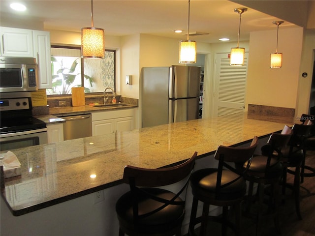2616 Cove Cay Dr Unit 104, Clearwater, FL 33760 - kitchen with appliances with stainless steel finishes, a sink, a kitchen bar, white cabinetry, and recessed lighting