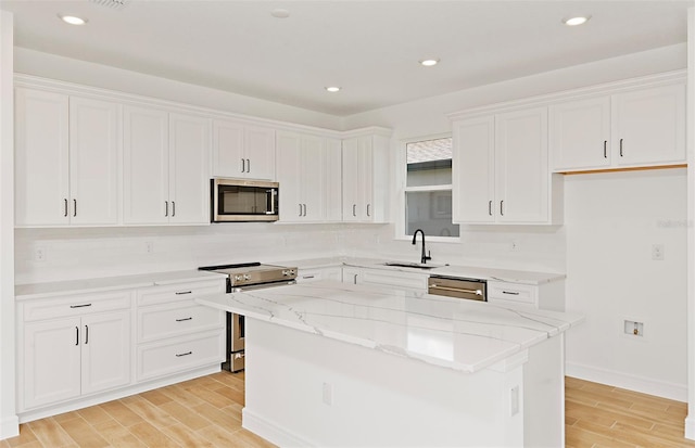 8323 SW 58th Loop, Ocala, FL 34481 - kitchen with appliances with stainless steel finishes, light wood-style flooring, white cabinetry, light stone countertops, and a center island