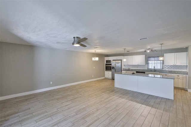 12372 113th St, Largo, FL 33778 - kitchen with appliances with stainless steel finishes, a ceiling fan, a center island, baseboards, and backsplash