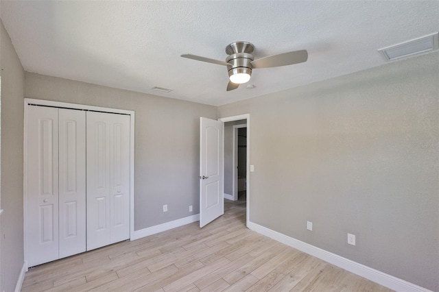 12372 113th St, Largo, FL 33778 - unfurnished bedroom with baseboards, light wood-style flooring, a closet, a ceiling fan, and a textured ceiling