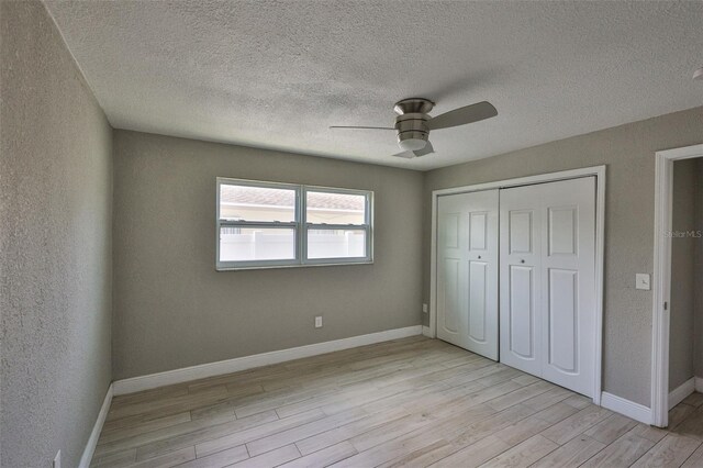 12372 113th St, Largo, FL 33778 - unfurnished bedroom with light wood finished floors, a closet, ceiling fan, baseboards, and a textured ceiling