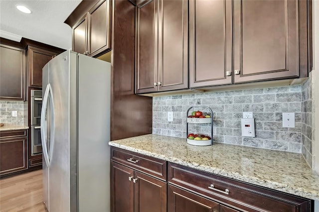 1821 Cherry Walk Rd, Lutz, FL 33558 - kitchen with appliances with stainless steel finishes, decorative backsplash, light stone counters, light wood finished floors, and dark brown cabinets