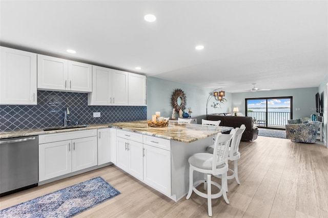 12525 3rd St E Unit 303, Treasure Island, FL 33706 - kitchen featuring stainless steel dishwasher, a sink, open floor plan, a peninsula, and white cabinetry