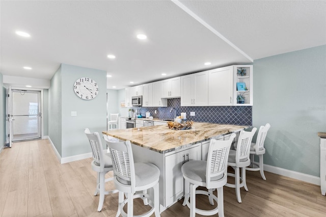 12525 3rd St E Unit 303, Treasure Island, FL 33706 - kitchen with appliances with stainless steel finishes, light stone counters, baseboards, white cabinets, and recessed lighting