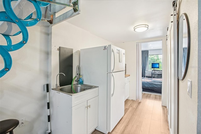 20921 Haulover Cv Unit 8, Lutz, FL 33558 - kitchen with white cabinets, freestanding refrigerator, light wood finished floors, a sink, and fridge