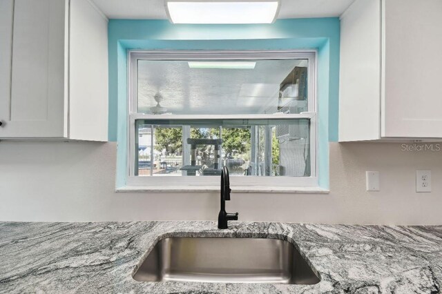 13323 Susan Dr, Hudson, FL 34667 - kitchen view of a sink, white cabinets, and light stone countertops
