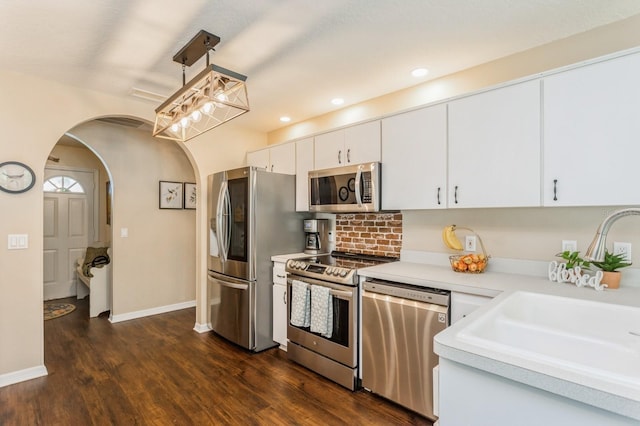 8549 Pinafore Dr, New Port Richey, FL 34653 - kitchen with appliances with stainless steel finishes, a sink, light countertops, arched walkways, and dark wood-style flooring
