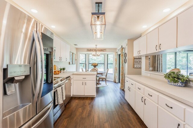 8549 Pinafore Dr, New Port Richey, FL 34653 - kitchen with appliances with stainless steel finishes, light countertops, a peninsula, dark wood-style floors, and a chandelier