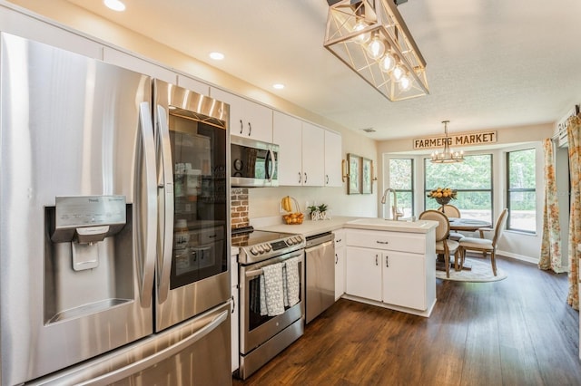 8549 Pinafore Dr, New Port Richey, FL 34653 - kitchen with appliances with stainless steel finishes, a chandelier, dark wood finished floors, white cabinets, and recessed lighting