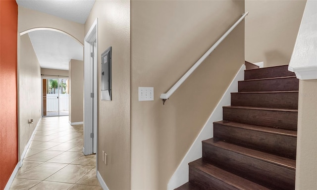 9752 Trumpet Vine Loop, Trinity, FL 34655 - stairs with tile patterned flooring, arched walkways, and baseboards