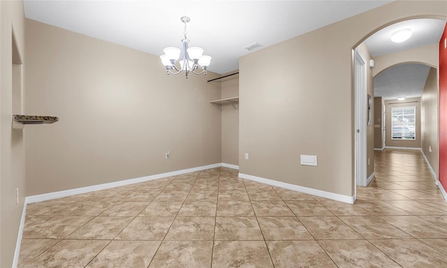 9752 Trumpet Vine Loop, Trinity, FL 34655 - spare room with arched walkways, a chandelier, light tile patterned floors, and baseboards