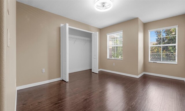 9752 Trumpet Vine Loop, Trinity, FL 34655 - unfurnished bedroom with dark wood-type flooring, baseboards, and a closet