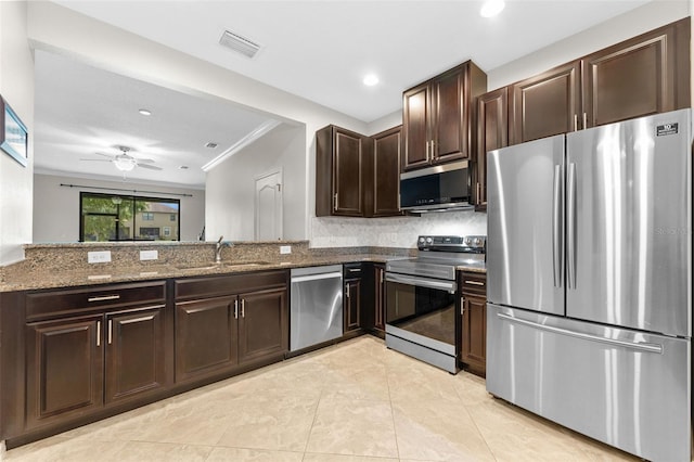 5153 Bay Isle Cir, Clearwater, FL 33760 - kitchen with appliances with stainless steel finishes, a sink, ornamental molding, dark stone countertops, and dark brown cabinets