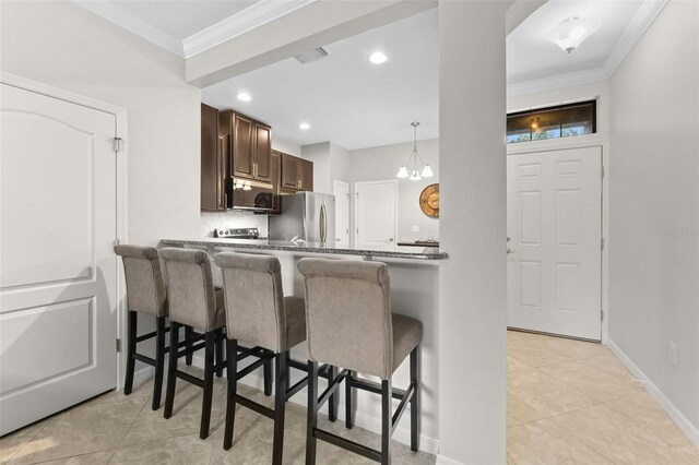 5153 Bay Isle Cir, Clearwater, FL 33760 - kitchen featuring freestanding refrigerator, a breakfast bar area, ornamental molding, dark brown cabinets, and light tile patterned flooring