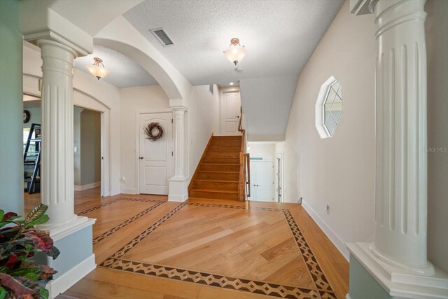 3397 Bluefish Dr, Hernando Beach, FL 34607 - entrance foyer with ornate columns, light wood-type flooring, stairs, and a textured ceiling