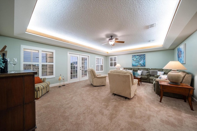 3397 Bluefish Dr, Hernando Beach, FL 34607 - living room featuring a tray ceiling, a ceiling fan, a textured ceiling, light carpet, and french doors