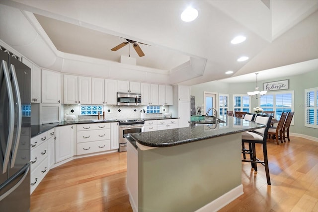 3397 Bluefish Dr, Hernando Beach, FL 34607 - kitchen featuring stainless steel appliances, a breakfast bar, a chandelier, tasteful backsplash, and light wood finished floors