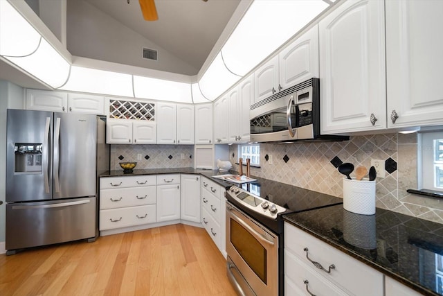 3397 Bluefish Dr, Hernando Beach, FL 34607 - kitchen featuring appliances with stainless steel finishes, vaulted ceiling, light wood-type flooring, and white cabinets