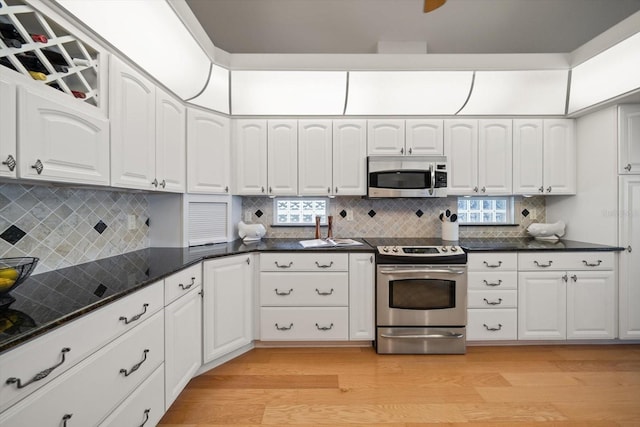 3397 Bluefish Dr, Hernando Beach, FL 34607 - kitchen featuring appliances with stainless steel finishes, light wood-type flooring, white cabinetry, and decorative backsplash