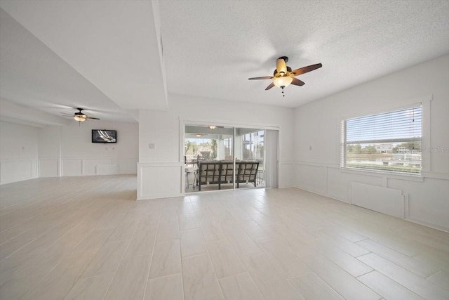3397 Bluefish Dr, Hernando Beach, FL 34607 - empty room featuring a ceiling fan, a decorative wall, a wainscoted wall, a textured ceiling, and light wood-style flooring