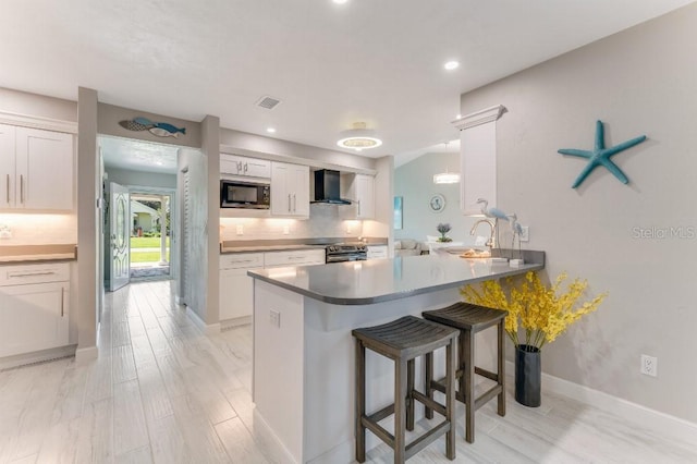 64 Alberta Ave, Ponce Inlet, FL 32127 - kitchen with built in microwave, wall chimney exhaust hood, stainless steel electric range oven, a peninsula, and a breakfast bar area