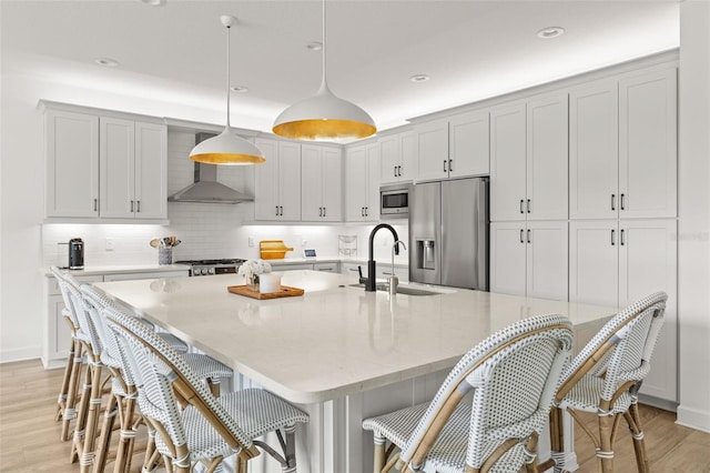 3541 Great Banyan Way, Wesley Chapel, FL 33543 - kitchen featuring stainless steel appliances, wall chimney range hood, light wood-type flooring, backsplash, and a spacious island