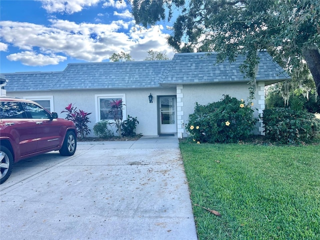 3725 Teeside Dr, New Port Richey, FL 34655 - view of front facade with roof with shingles, mansard roof, stucco siding, a front yard, and concrete driveway