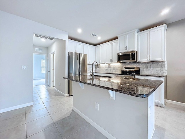 10347 Heron Hideaway Loop, Land O Lakes, FL 34638 - kitchen featuring appliances with stainless steel finishes, a sink, backsplash, dark stone counters, and light tile patterned floors