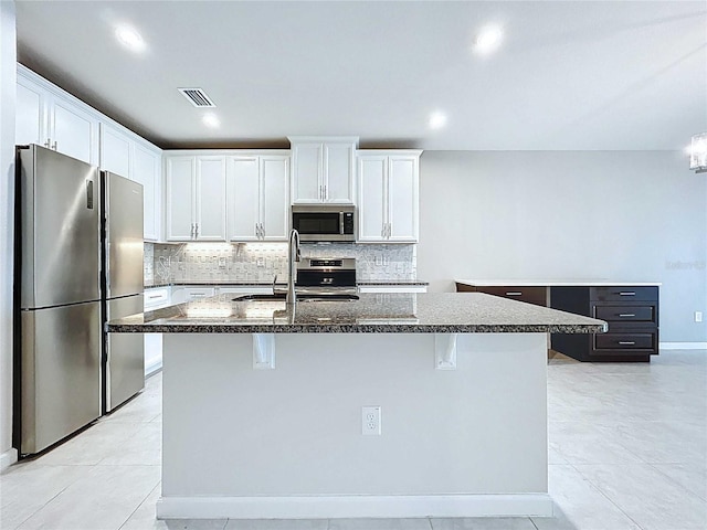 10347 Heron Hideaway Loop, Land O Lakes, FL 34638 - kitchen with stainless steel appliances, a kitchen island with sink, a sink, tasteful backsplash, and white cabinetry