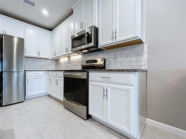 10347 Heron Hideaway Loop, Land O Lakes, FL 34638 - kitchen featuring appliances with stainless steel finishes, backsplash, white cabinets, light tile patterned floors, and dark stone counters
