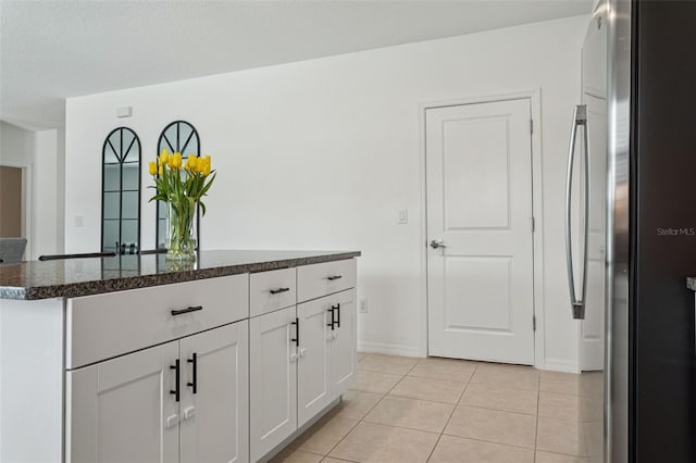 11693 Lavender Loop, Spring Hill, FL 34609 - kitchen featuring freestanding refrigerator, light tile patterned floors, white cabinetry, dark stone countertops, and a kitchen island