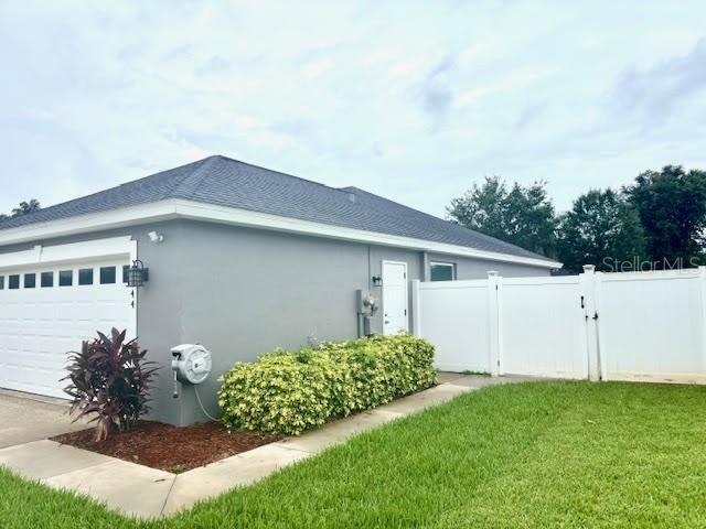 7144 Remington Oaks Loop, Lakeland, FL 33810 - view of side of home featuring a garage, stucco siding, and a gate