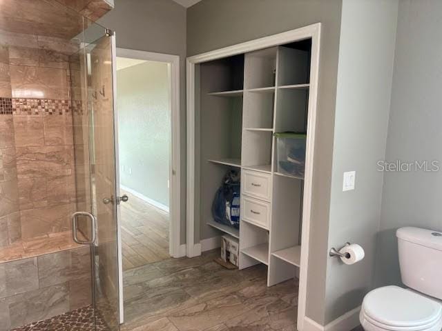 7144 Remington Oaks Loop, Lakeland, FL 33810 - full bathroom featuring a stall shower, toilet, and baseboards