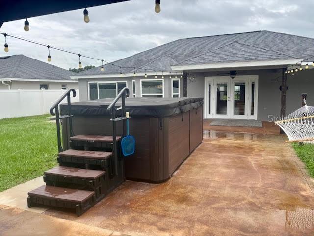 7144 Remington Oaks Loop, Lakeland, FL 33810 - back of property featuring a hot tub, french doors, a shingled roof, and a patio area